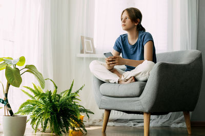 Young woman using laptop while sitting on sofa at home