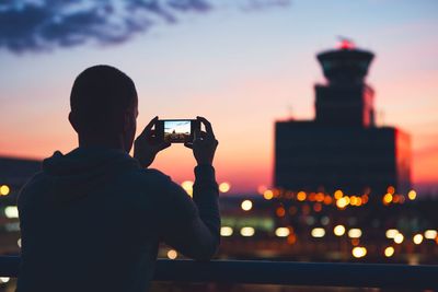 Rear view of man photographing at sunset