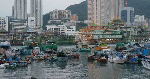 Boats moored on river by buildings in city