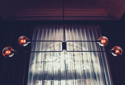 Low angle view of illuminated light bulb hanging from ceiling