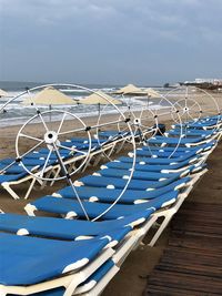 Deck chairs on beach against blue sky