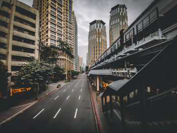 Road by buildings against sky in city