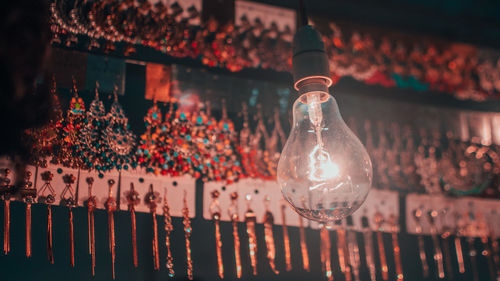 Close-up of illuminated light bulbs hanging from glass