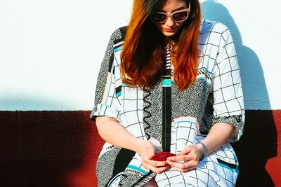 Young woman sitting against wall