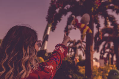 Close-up of young woman against trees during sunset