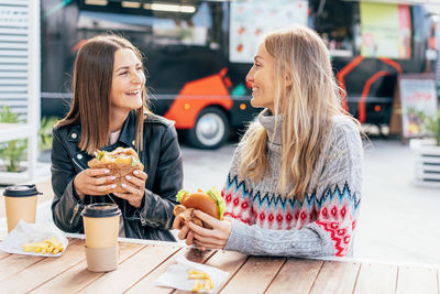 Portrait of smiling friends using mobile phone in cafe