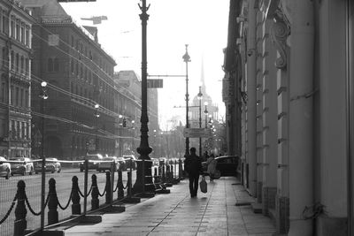 People walking on footpath amidst buildings in city