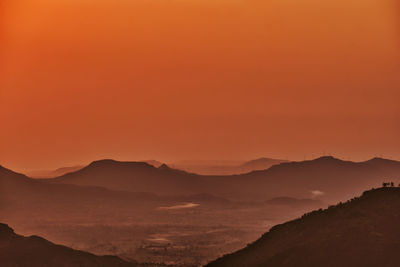 Scenic view of silhouette mountains against orange sky