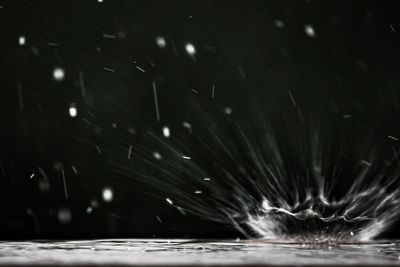 Water drops on glass against sky at night