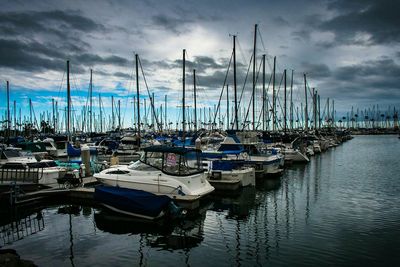 Boats moored in sea against cloudy sky