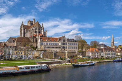 Buildings by river against sky in city