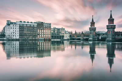 Reflection of oberbaumbruecke and buildings on spree river at sunset