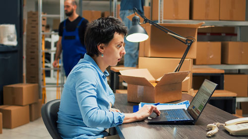 Side view of woman using laptop while sitting on table