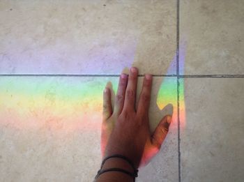Close-up of woman hand on multi colored water