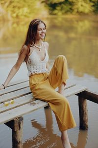 Young woman sitting on pier over lake