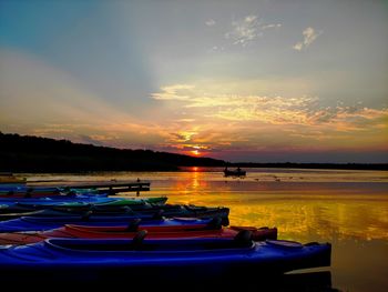 Boats moored in lake against sky during sunset