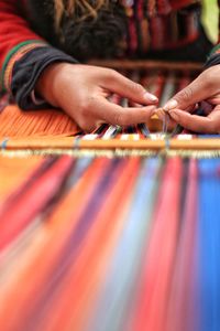 Midsection of person weaving loom