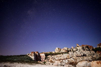 Rocks on field against sky at night