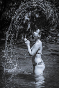 Side view of teenage girl tossing hair in lake