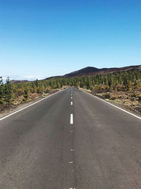 Empty road against clear blue sky