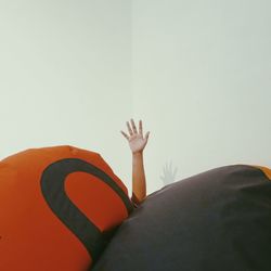 Cropped hand amidst bean bag against wall at home