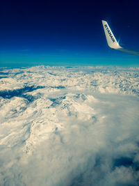 Aerial view of cloudscape and airplane wing against sky