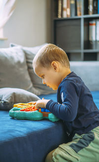 Side view of boy sitting on sofa at home