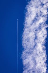 Low angle view of vapor trail against blue sky