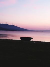 Silhouette boat on beach against sky during sunset