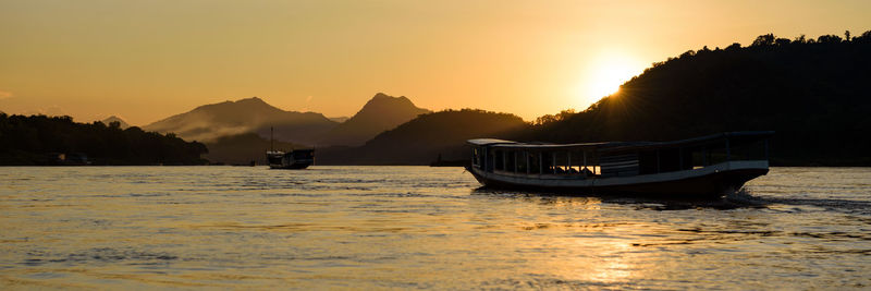 Boats in sea at sunset