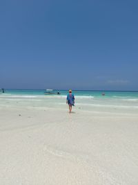 Rear view of man on beach against clear sky