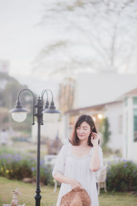 Woman standing by street light against sky