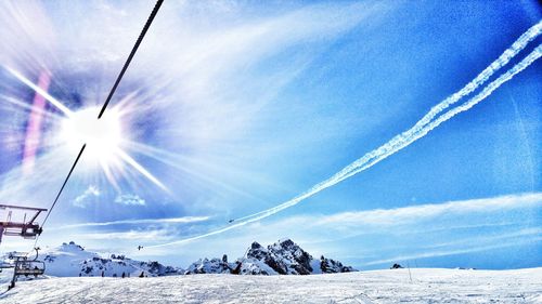 Low angle view of ski lift against blue sky