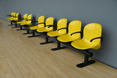 Deserted yellow seats on gray wall at waiting room woodden floor