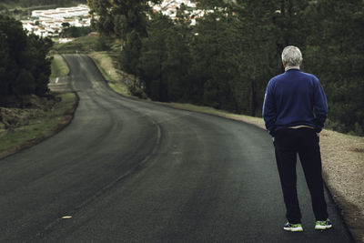 Rear view of senior man standing on road 