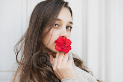 Portrait of young woman with long hair holding flower