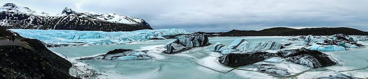 Scenic view of snow covered mountains against cloudy sky