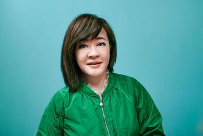 Portrait of young woman against blue background