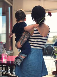 Mother carrying son while standing in restaurant