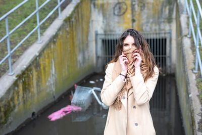 Portrait of young woman standing against wall