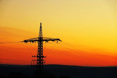 Silhouette electricity pylon against romantic sky at sunset