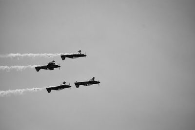 Four aerobatic planes flying up side down in clear sky.