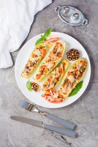 Ready-to-eat baked zucchini halves stuffed with cheese and tomato and basil leaves on a plate 