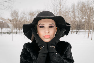 Portrait of young woman in warm clothing standing at park during winter
