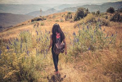 Portrait of young woman with arms outstretched standing on landscape