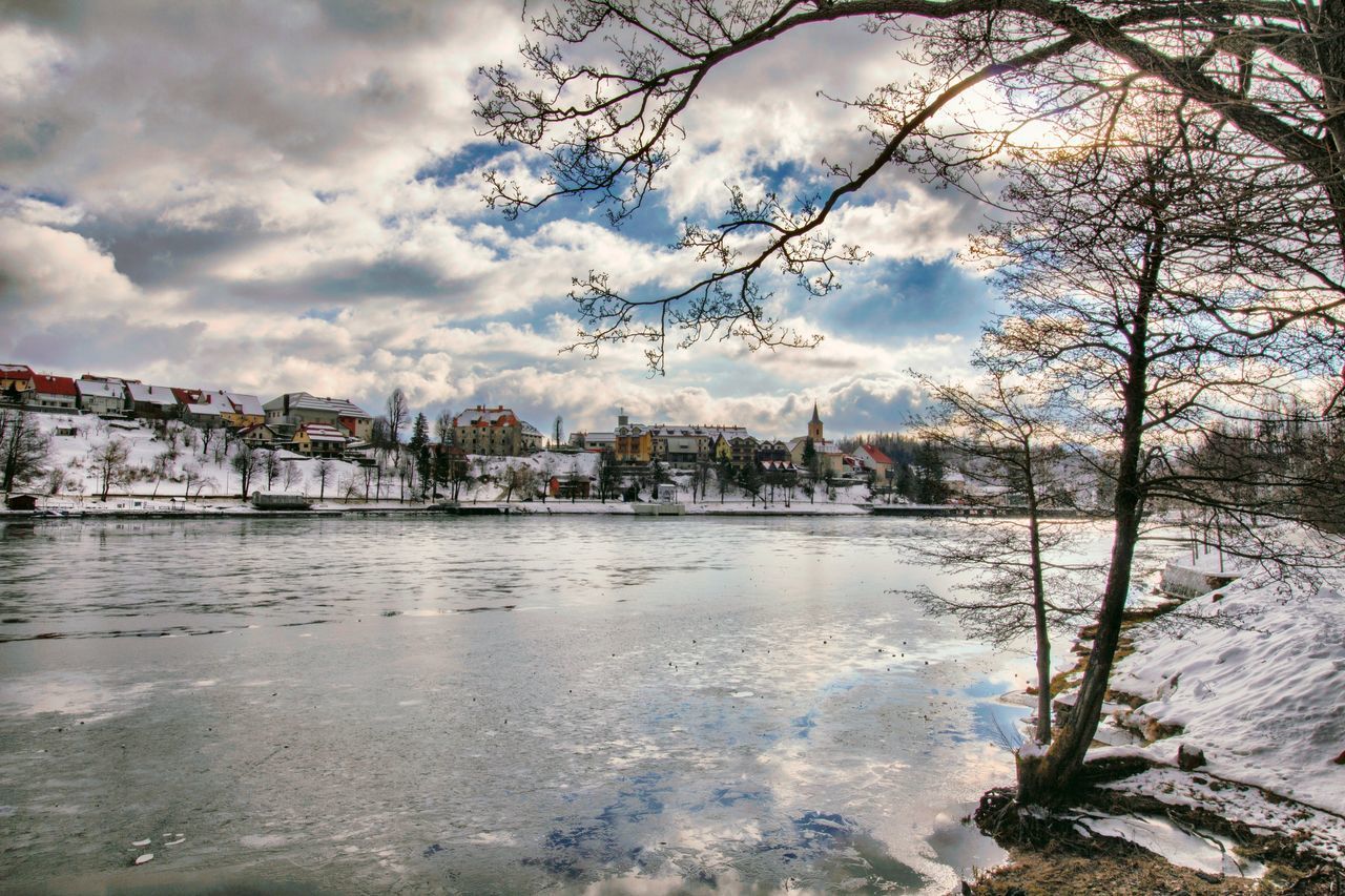 BUILDINGS BY RIVER AGAINST SKY