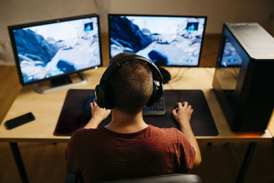 Young man playing video games with computer at desk