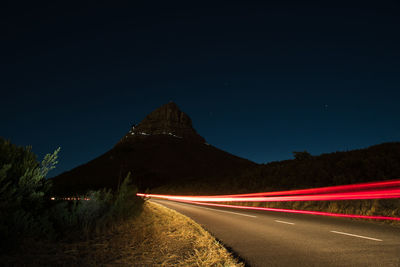 Light trails on road against clear sky at night