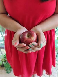 Midsection of woman holding red fruit