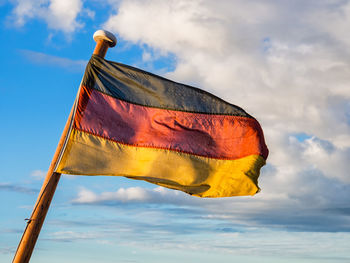 Low angle view of german flag waving against cloudy sky